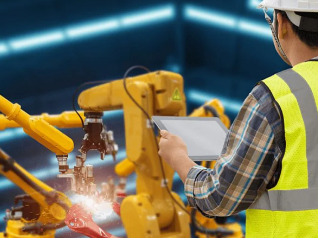 Falha significa maior custo. Na imagem, um funcionário de colete amarelo e capacete de segurança faz a inspeção de um equipamento industrial a partir de um tablet.